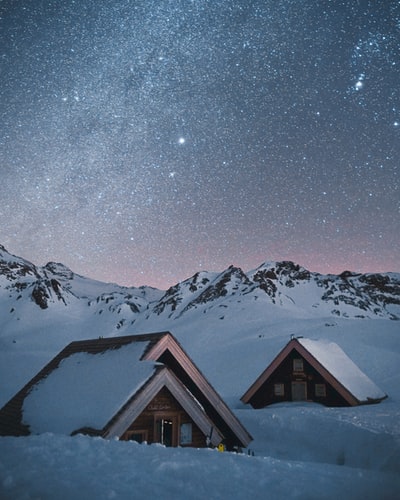 棕色的木头房子在夜间地面上冰雪覆盖
